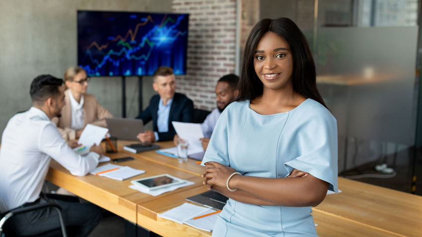 Black business woman in a boardroom smiling towards the camera