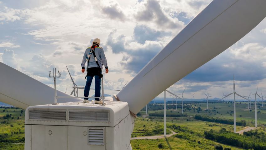 Man looking out over wind turbines to an optimistic future